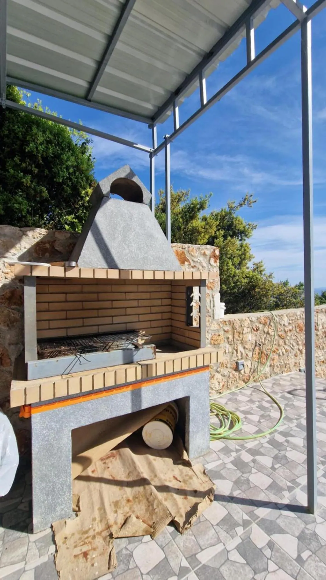 A built stone barbecue at the end of the kitchen terrace at Ionian Pearl, under the edge of the steel roof