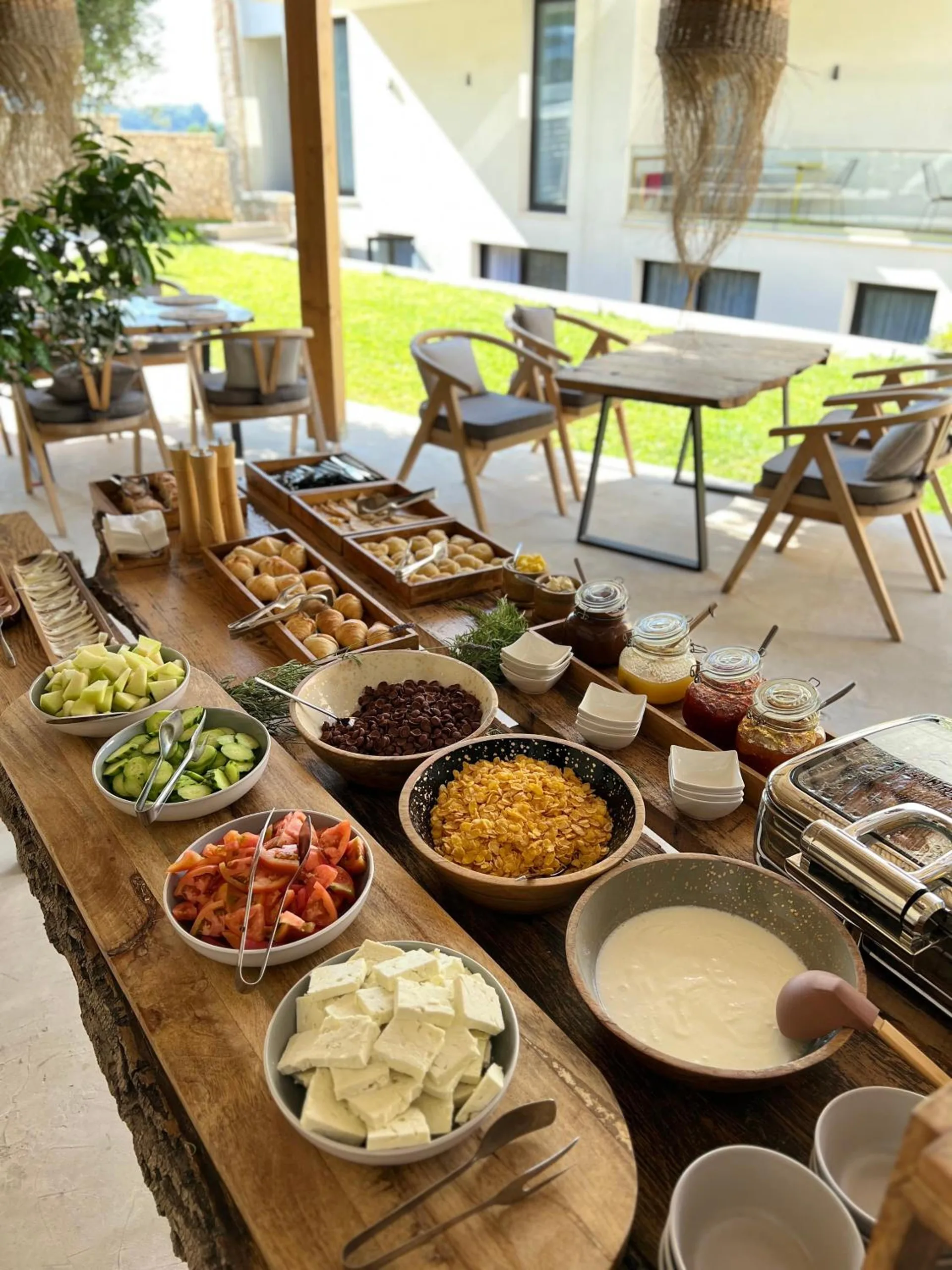 The breakfast board running along the terrace towards tables on the lawn, the hotel's glass balconies above