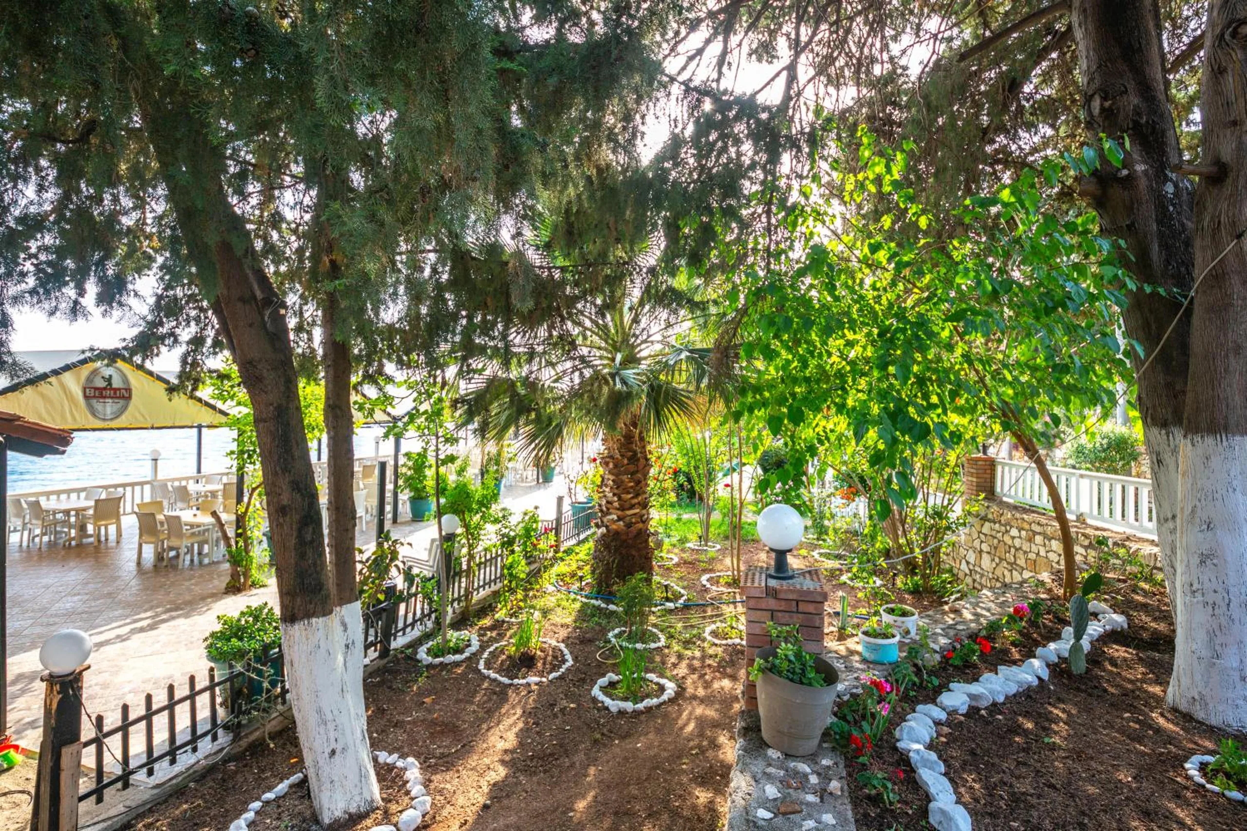 A garden of white-limed tree trunks, pebble-edged beds and lamps leading to the restaurant deck and the sea