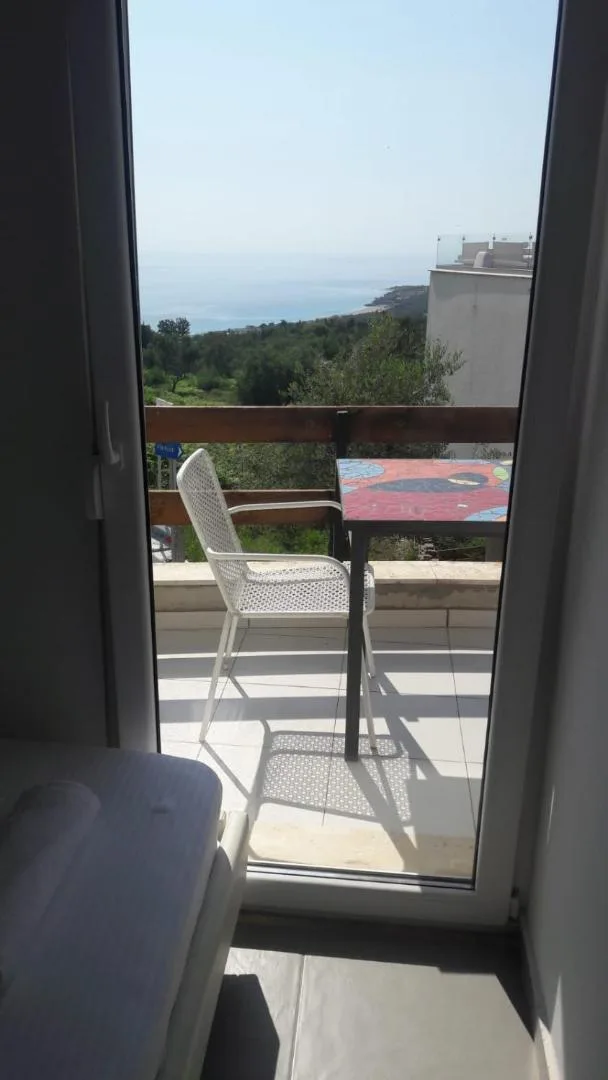 A white metal chair on a balcony looking out over the green hillside
