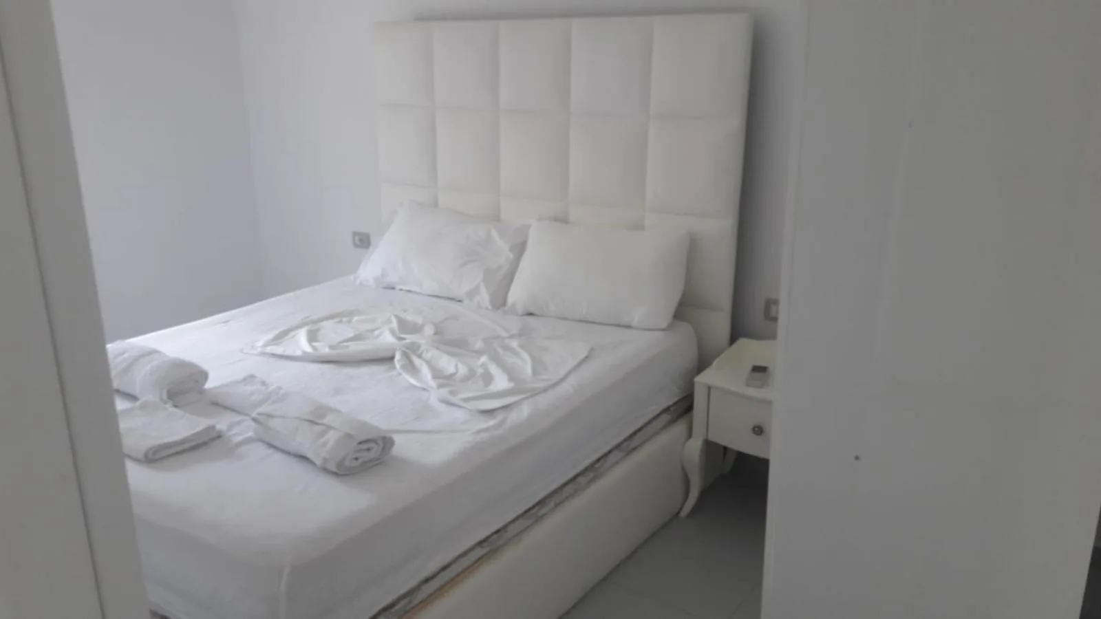 A double bed with a padded white headboard