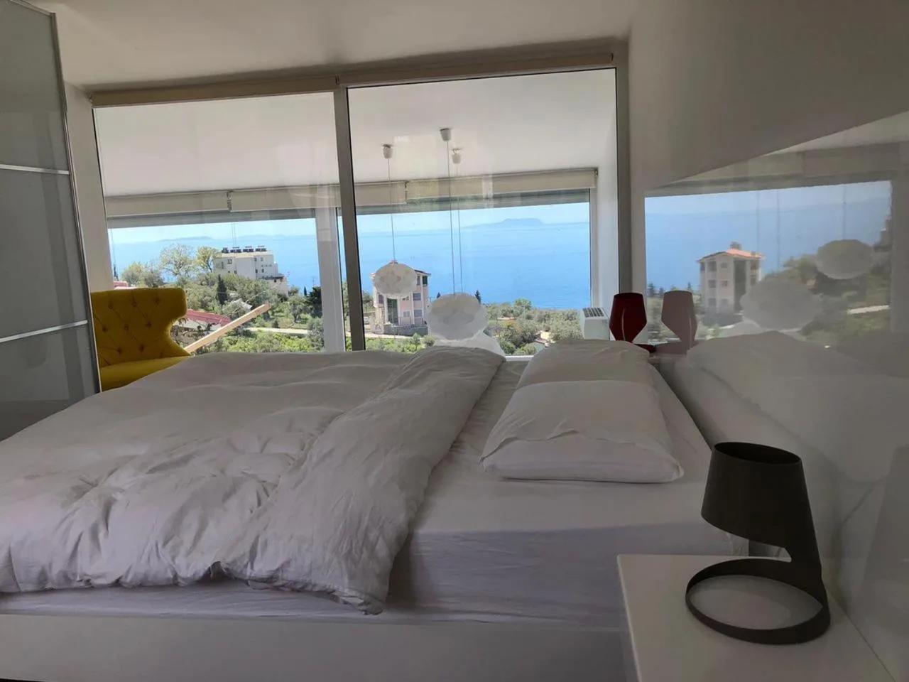 A bed under a full-width window that looks out over the hillside to the sea