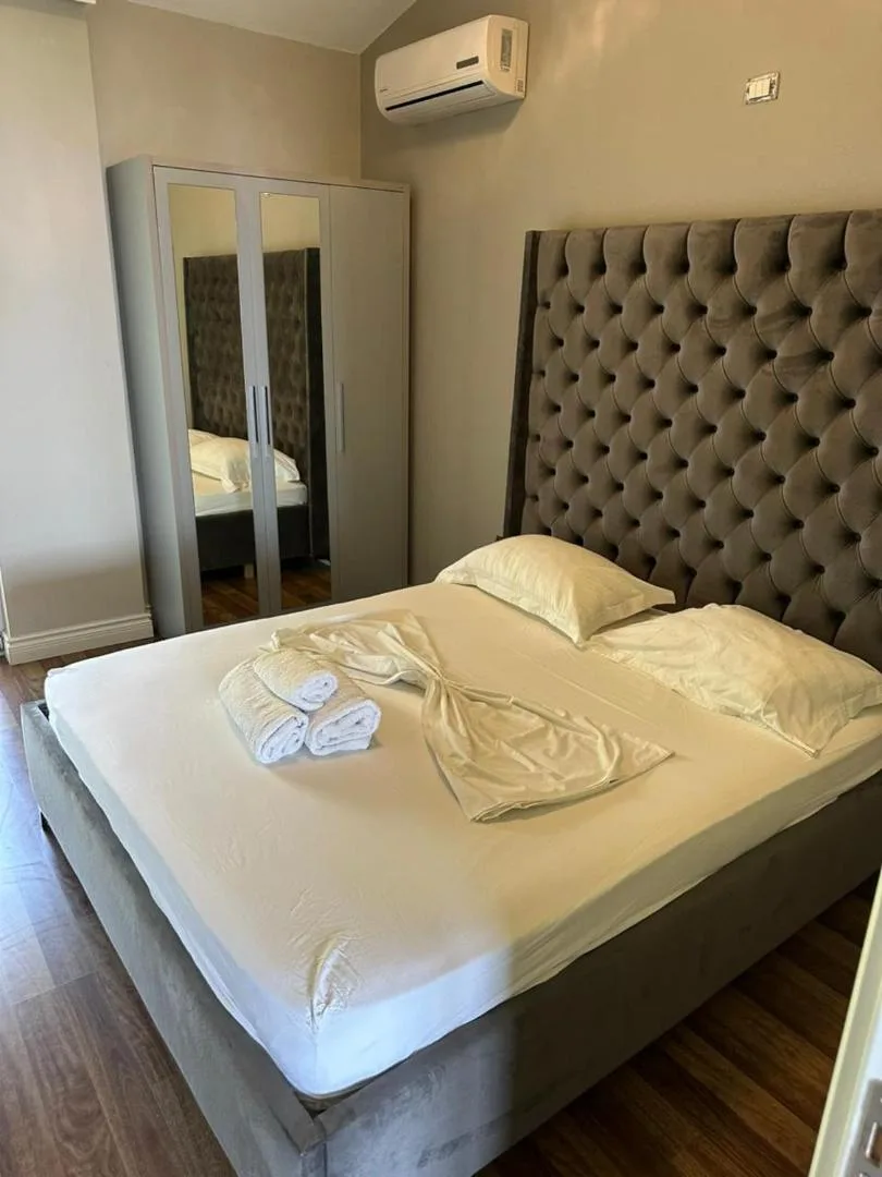 A double bed with a tall buttoned headboard in a villa bedroom