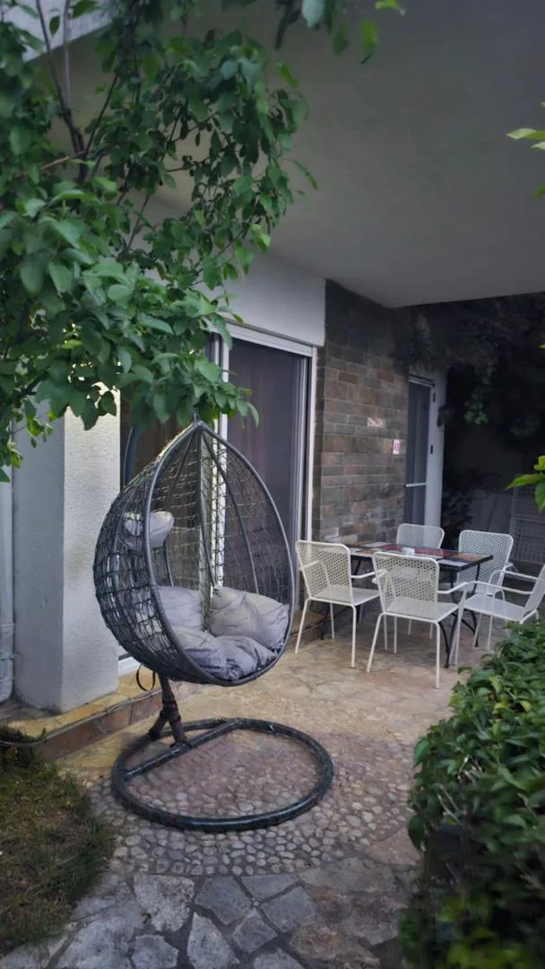A hanging egg chair and a set table on a villa's stone patio, with grey stone cladding behind