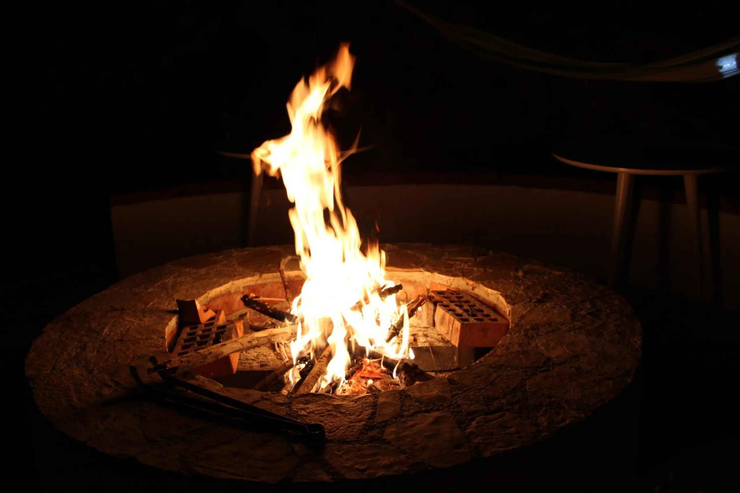 Flames rising from logs in the stone-rimmed fire pit, in darkness