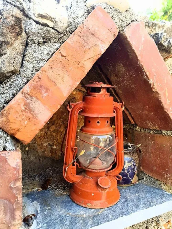 An orange paraffin lantern in a small brick niche beside a blue-patterned tile