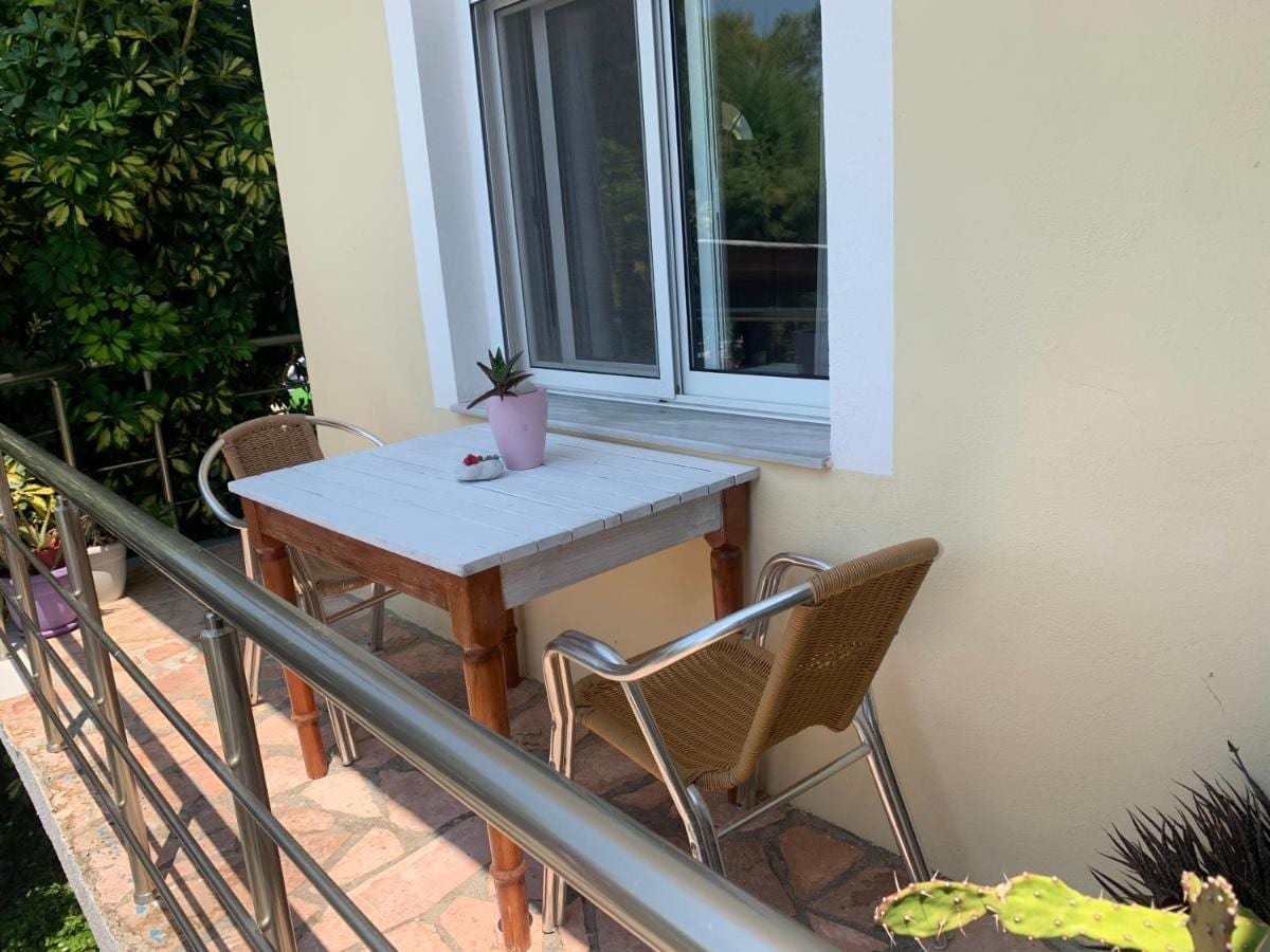 A small painted table and two chairs on a balcony beside a window, a potted succulent on the table