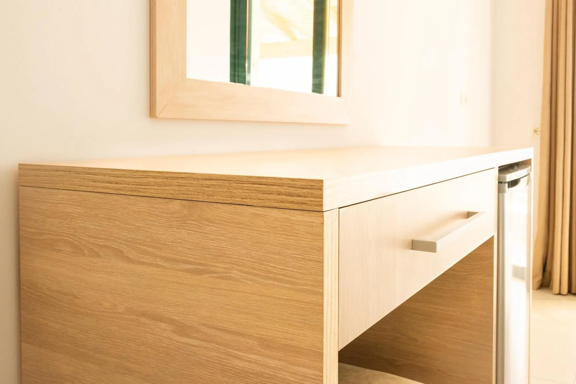 An oak desk with a drawer and a small fridge below a mirror