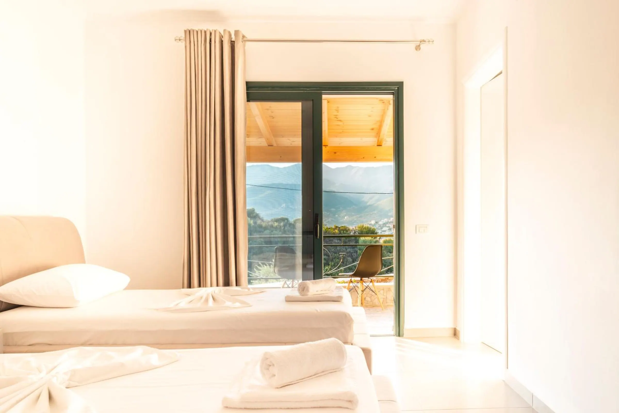 A bed in the family room and a glass door open onto the balcony, the bay and the mountains beyond