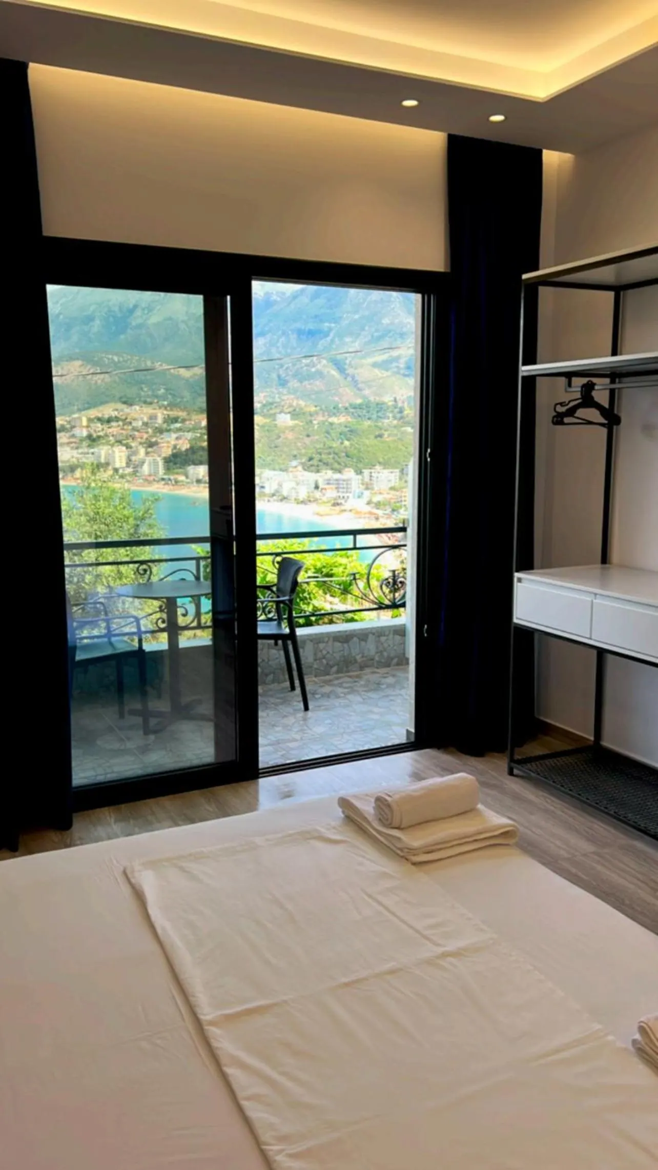 A balcony door open onto a table on the balcony, the bay and the town below