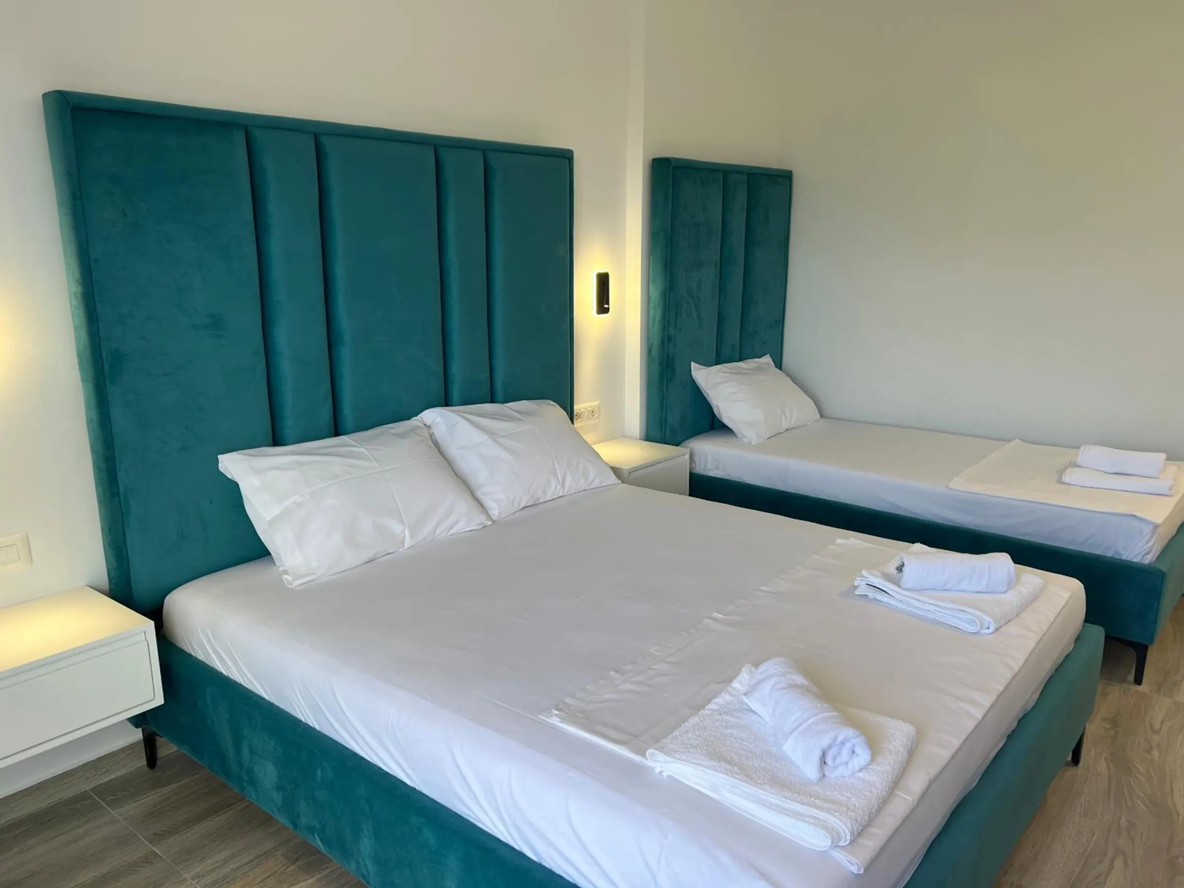 Tall teal velvet headboards over a double bed and a single