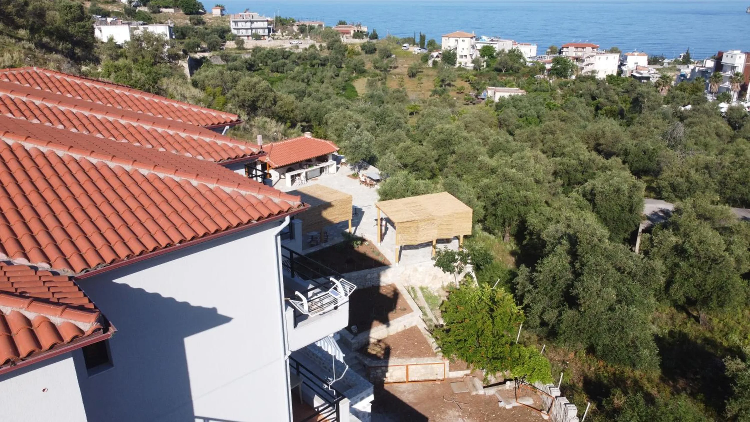 Terracotta roofs of the house seen from above, with the olive grove running down the hill to the houses of Potam and the sea