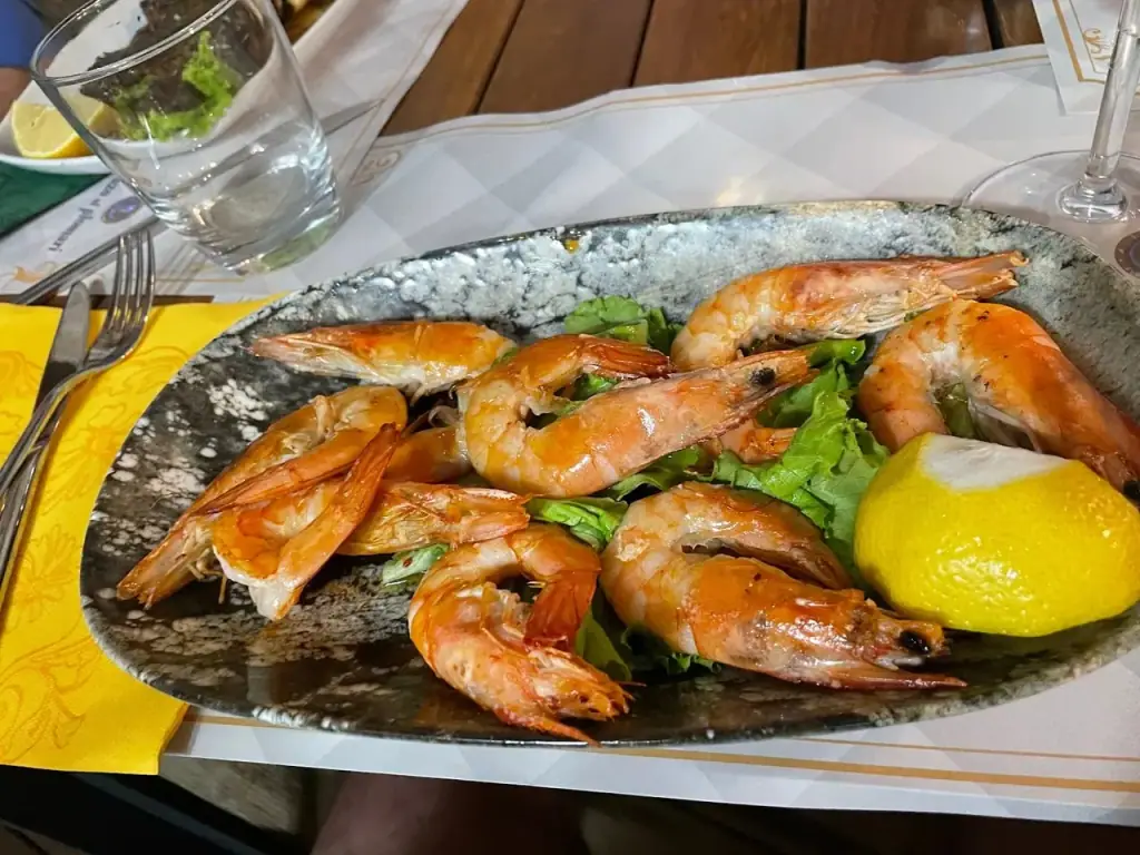 Whole cooked prawns on lettuce leaves on a speckled grey oval platter, with half a lemon
