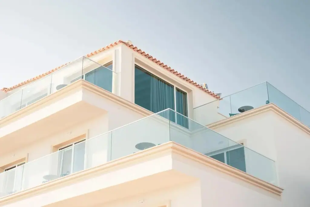 The top floor seen from below: cream cornices, terracotta pantiles and glass balustrades against the sky