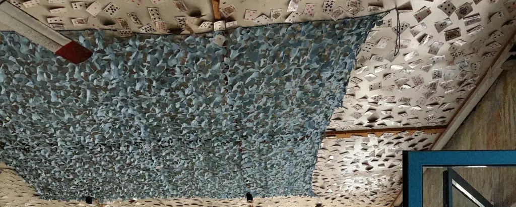 Playing cards pasted across the ceiling of Bar 300 with blue camouflage netting hung beneath them