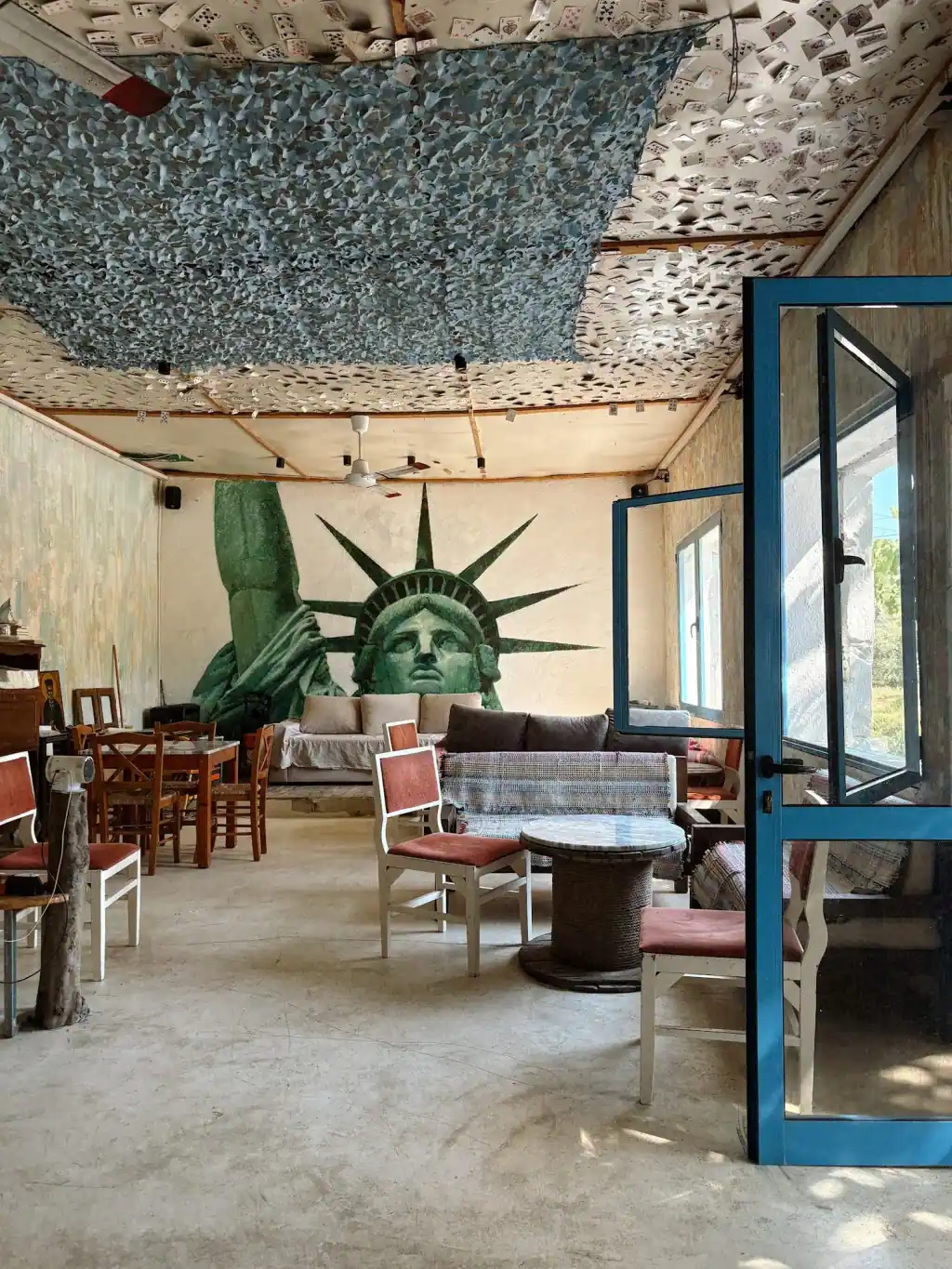 The lounge at Bar 300 with the Statue of Liberty painted across the back wall, sofas, kilim-covered benches and marble tables on cable reels
