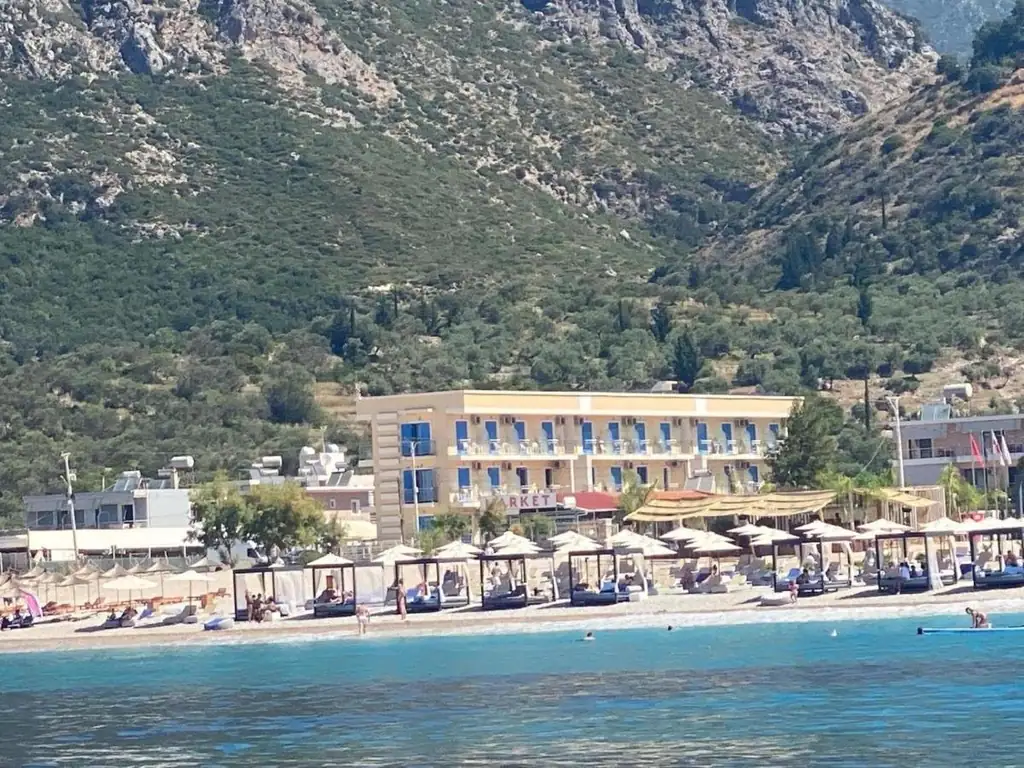 Blue Horizon seen from the water, its balconies above the loungers and cabanas on Livadhi Beach