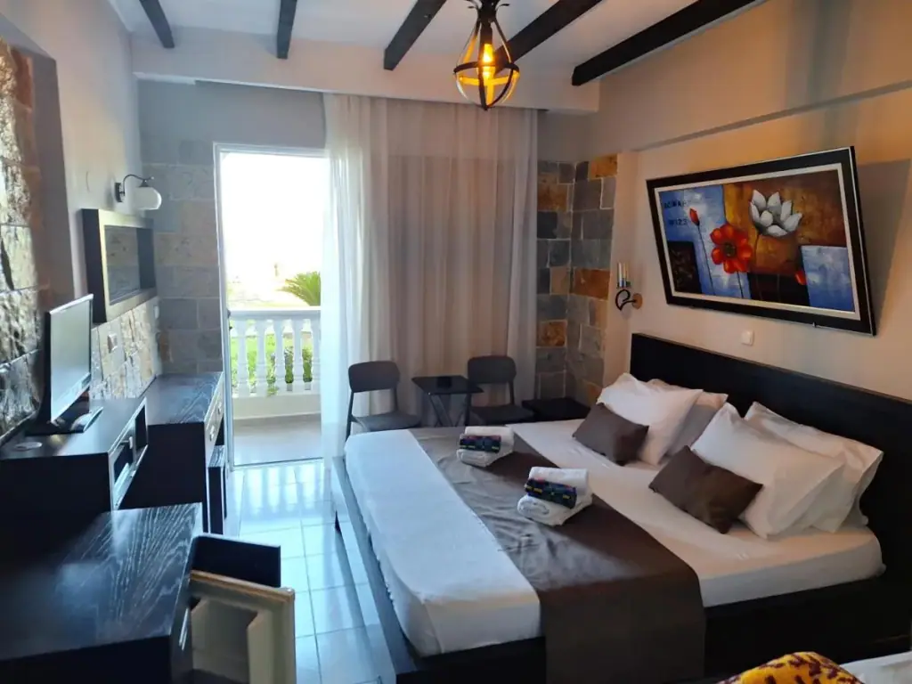A guest room at Castle Hotel with exposed dark beams, a wrought-iron lantern, split-face stone on the walls and a balcony behind sheer curtains