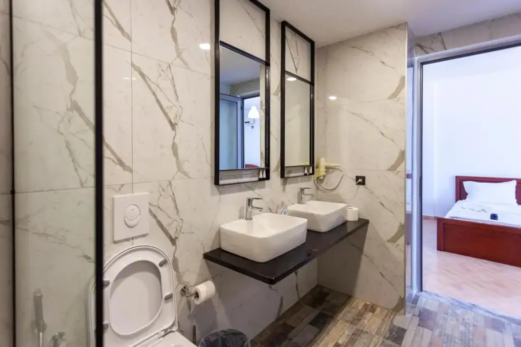 A marble bathroom with two square basins and black-framed mirrors