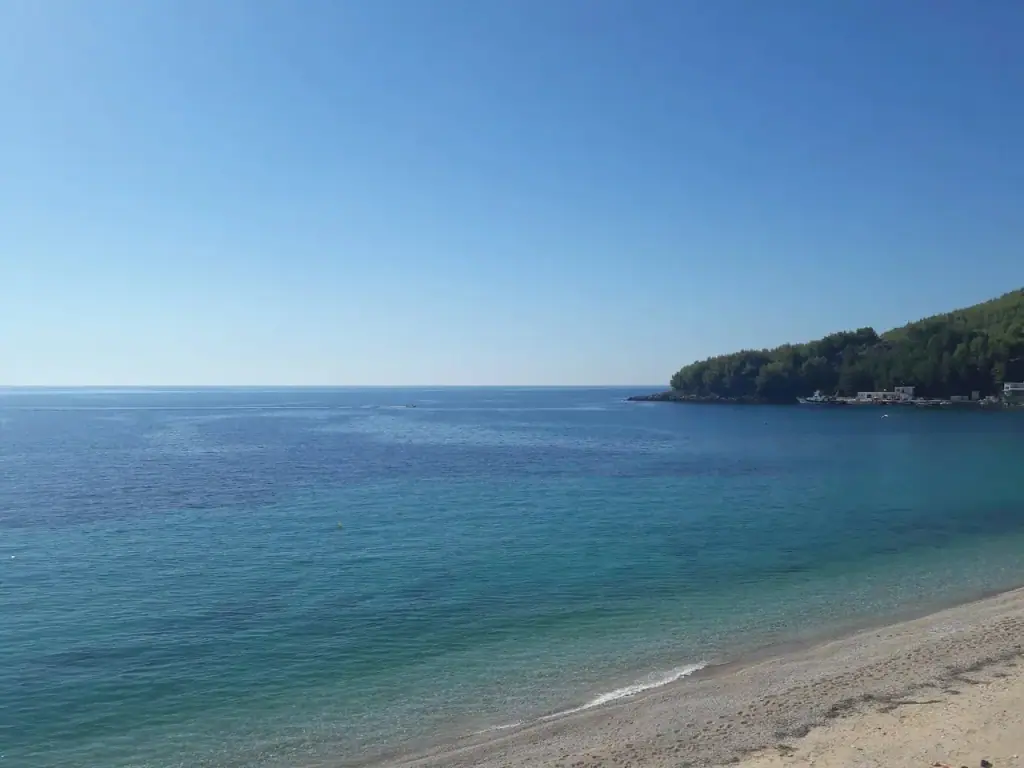 A quiet turquoise cove closed off by a wooded headland