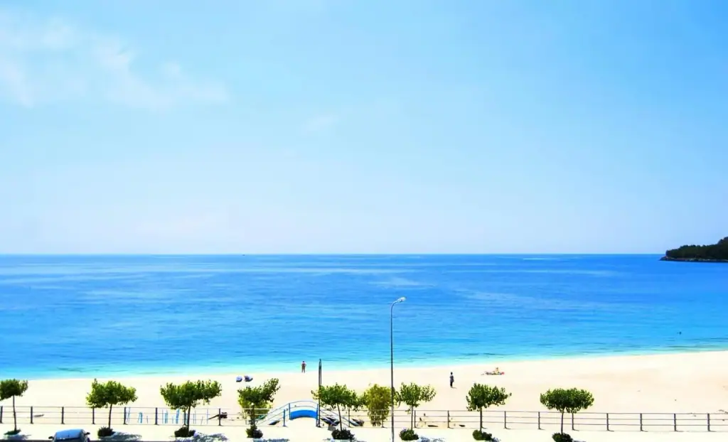 The beach and the coast road seen from an upper balcony, with clear blue water