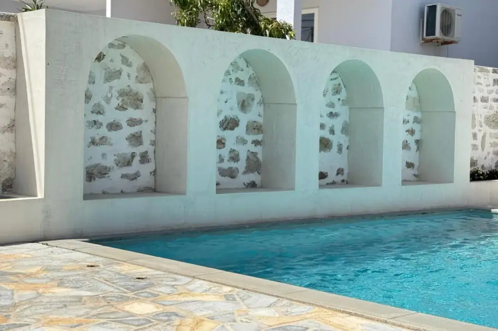 Four round-headed niches cut into the whitewashed wall beside the pool at Dimitri Hotel, each one opening onto bare limestone rubble