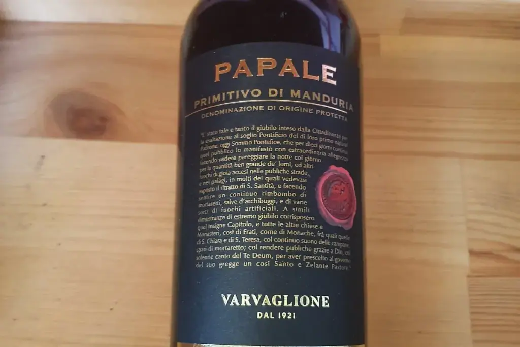 A bottle of Papale Primitivo di Manduria, Varvaglione, on a pine table