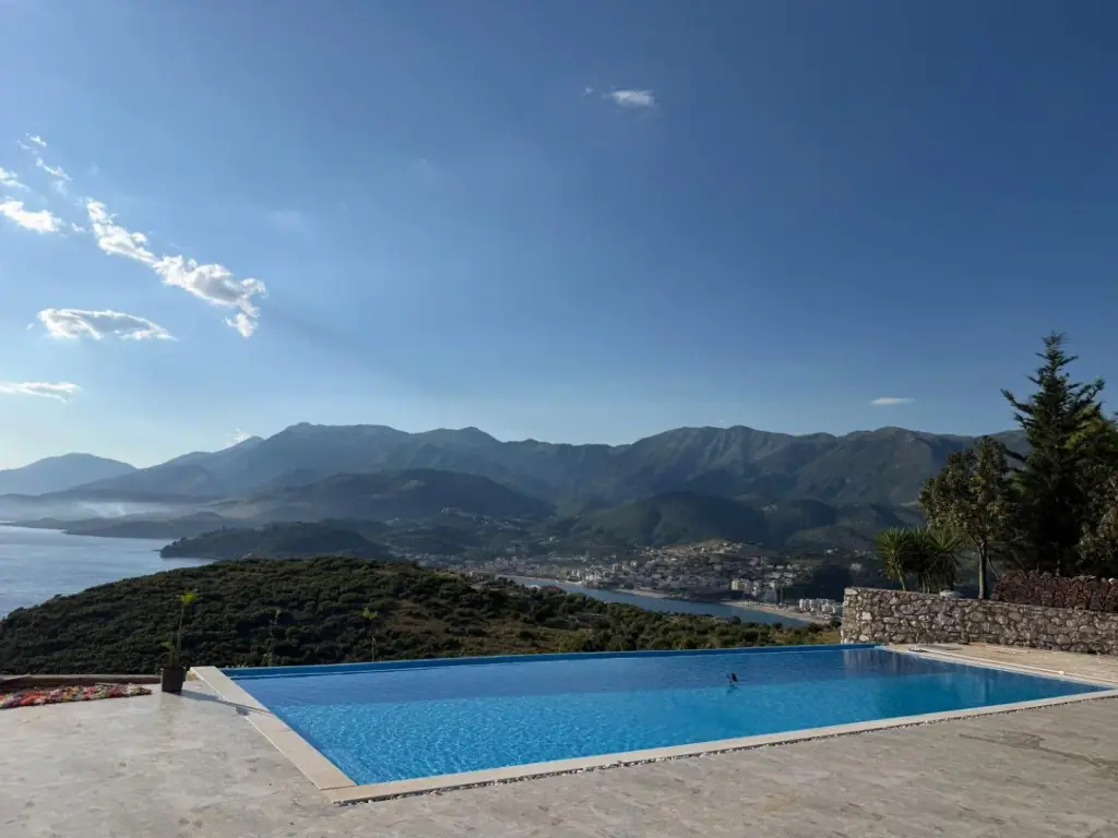 The pool seen along its length, the mountains across Himarë bay filling the horizon