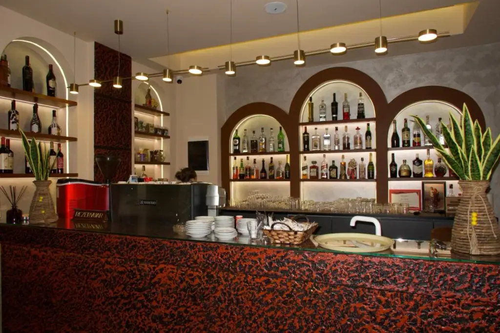The bar at Hotel Frida: arched backlit niches of bottles above a counter faced in mottled red and black