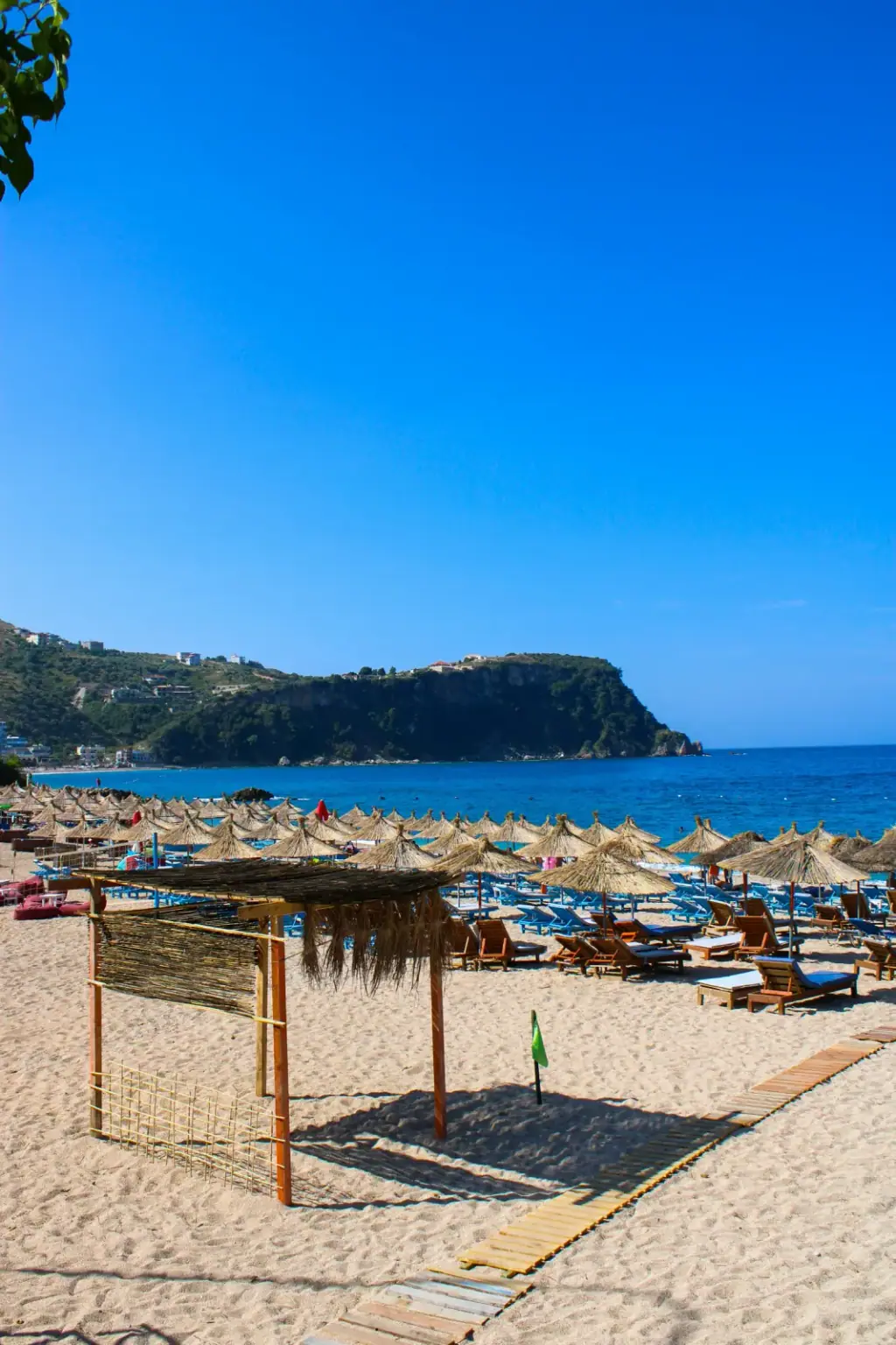 Summer umbrellas and beach crowd atmosphere representing Himara beach clubs