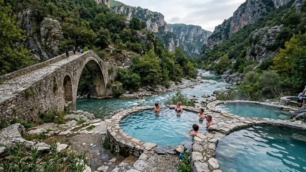Stone-rimmed turquoise hot-spring pools beside an old Ottoman bridge and canyon near Përmet