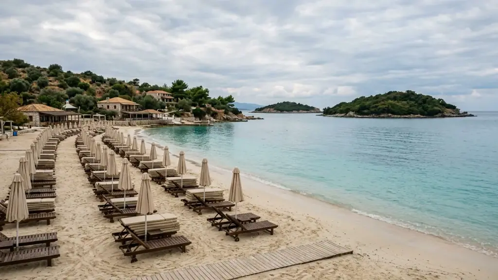 Empty Ksamil beach in October with calm turquoise water, stacked sunbeds and overcast autumn sky