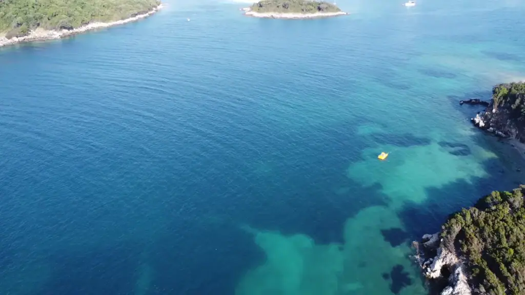 Aerial view of Ksamil's shallow turquoise water and pale sand with small wooded islets just offshore