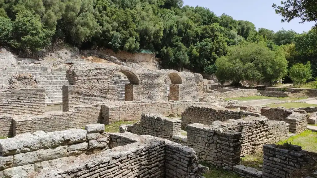 Roman-era stone ruins and arches at Butrint standing among long grass and trees