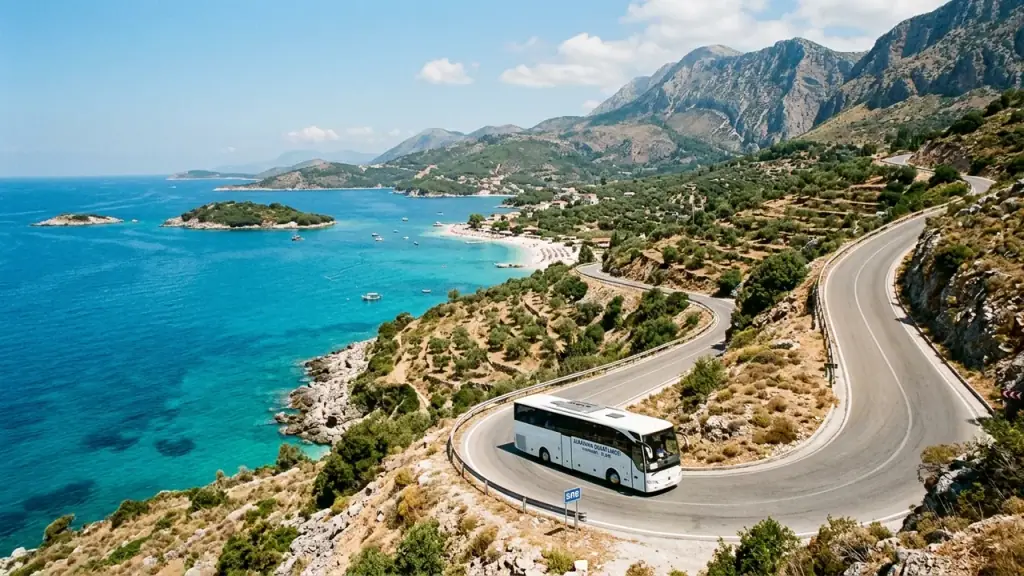 A white coach on a winding coastal road high above a turquoise bay on the Albanian Riviera