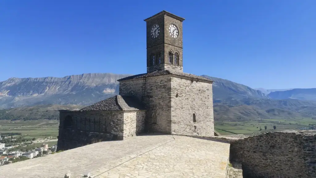 The stone clock tower of Gjirokastër castle standing above the town with bare mountains behind