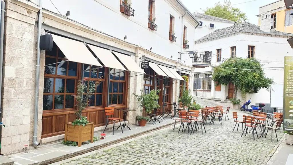 A stone-paved street in Gjirokastër's old town lined with cafés and shuttered stone buildings