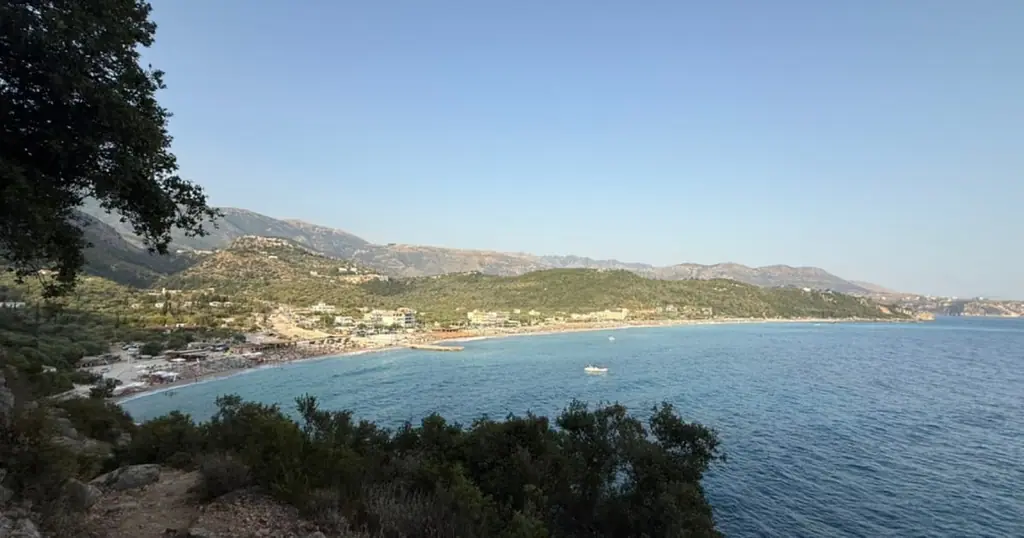 Livadhi Beach and its bay seen from the hillside above, the Ionian Sea calm below the coastal mountains