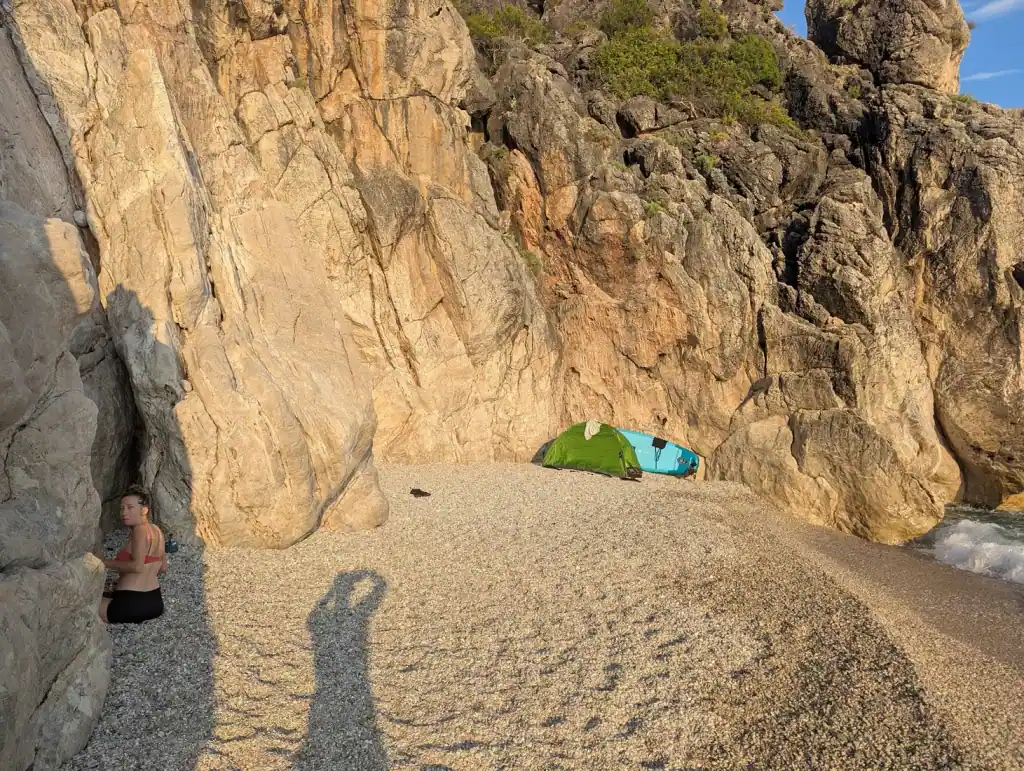 Tents pitched on the pebbles at Couple's Bay beneath the cliff