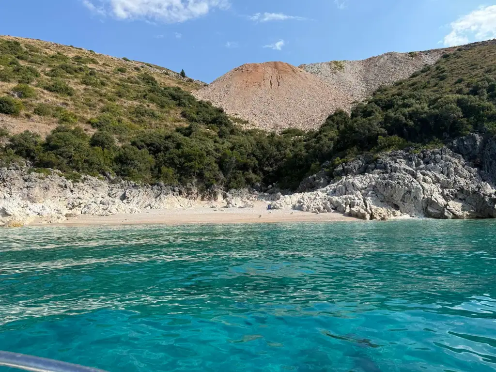 Turquoise water and the pebble shore at Crystal Beach below its scree slope