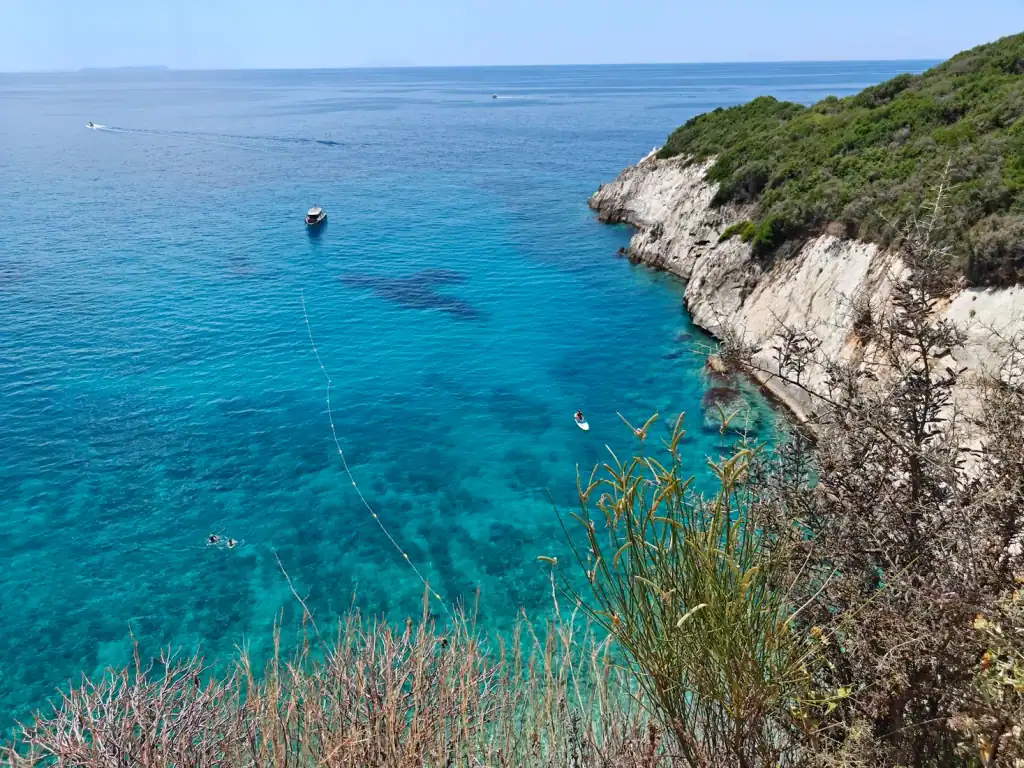 Turquoise shallows and anchored boats below the Filikuri cliffs
