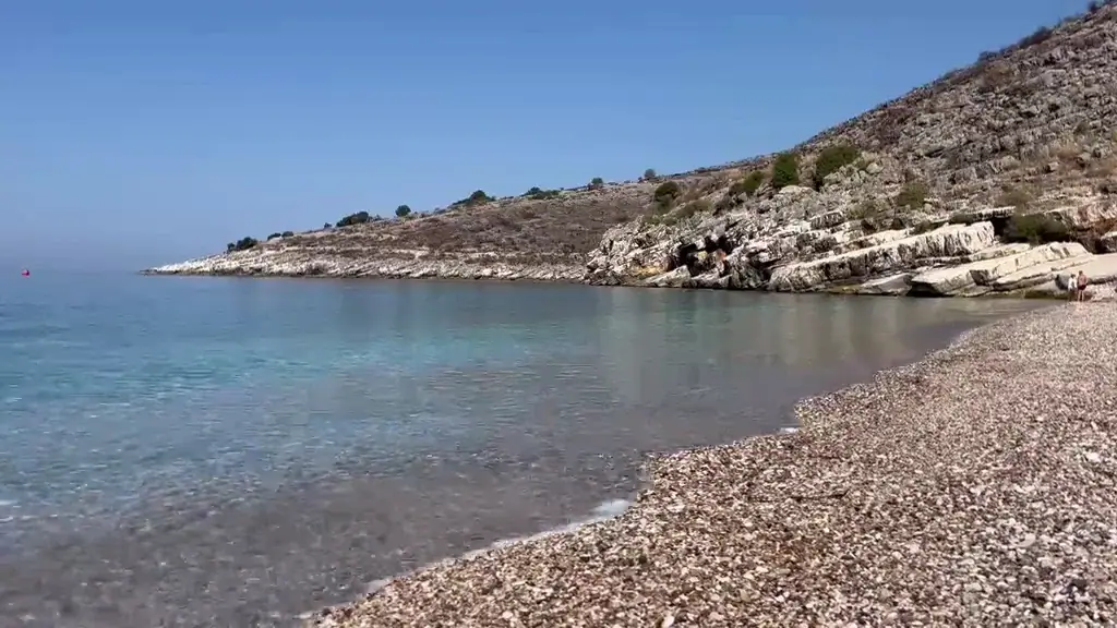 Pebbles and clear shallow water at the Llamani shoreline