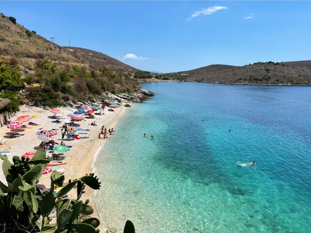Umbrellas along the Porto Palermo beach beside turquoise water