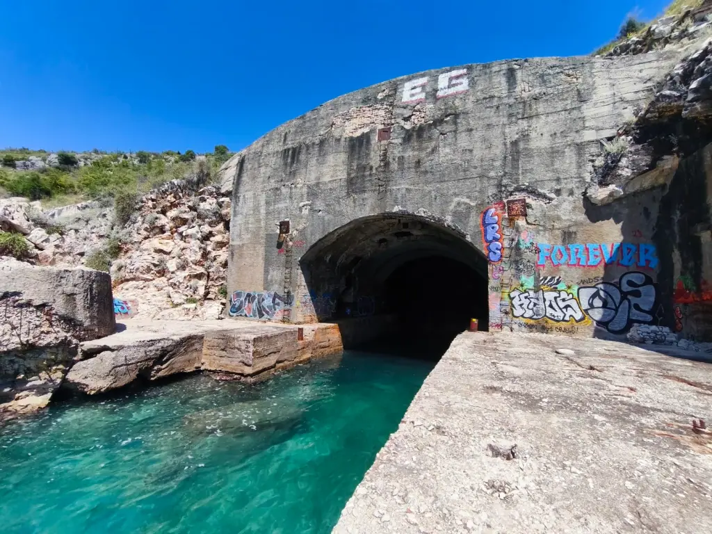 Graffitied tunnel entrance above the turquoise channel