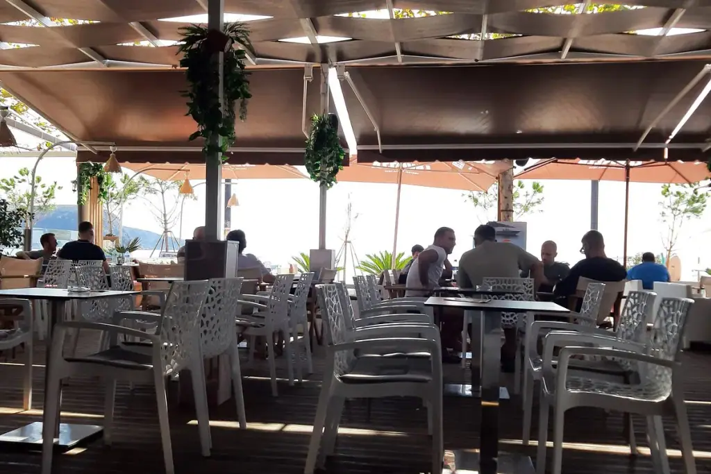 Lido Lounge bar interior with shisha, lit drinks shelves and neon bar sign on the Himara seafront