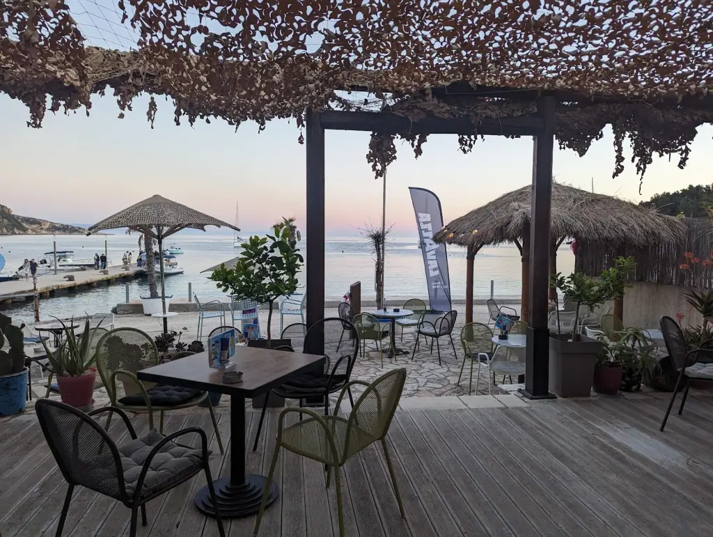 Sunset view of the Ionian sea from Manolo Beach Bar's wooden deck on Spile promenade