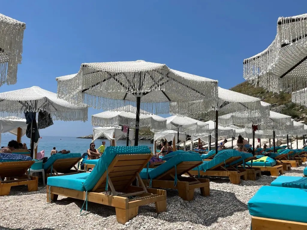 Mumbas Beach Club's fringed white umbrellas and turquoise-cushioned loungers on Llaman Beach