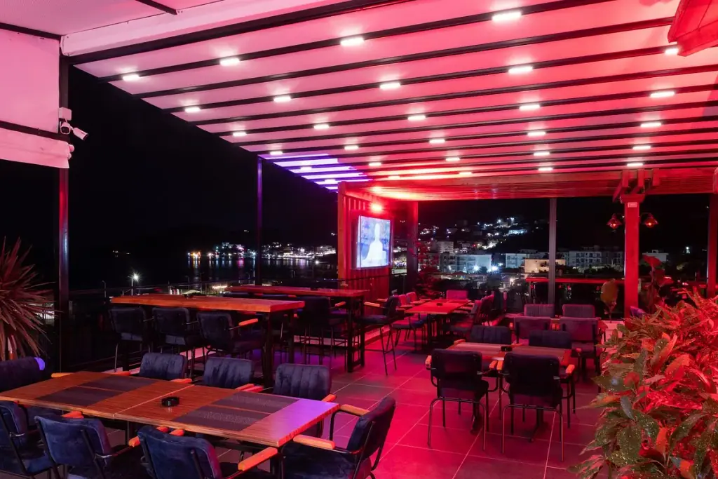 Rooftop Nia Boutique's pergola-covered terrace seating overlooking Himara bay at sunset