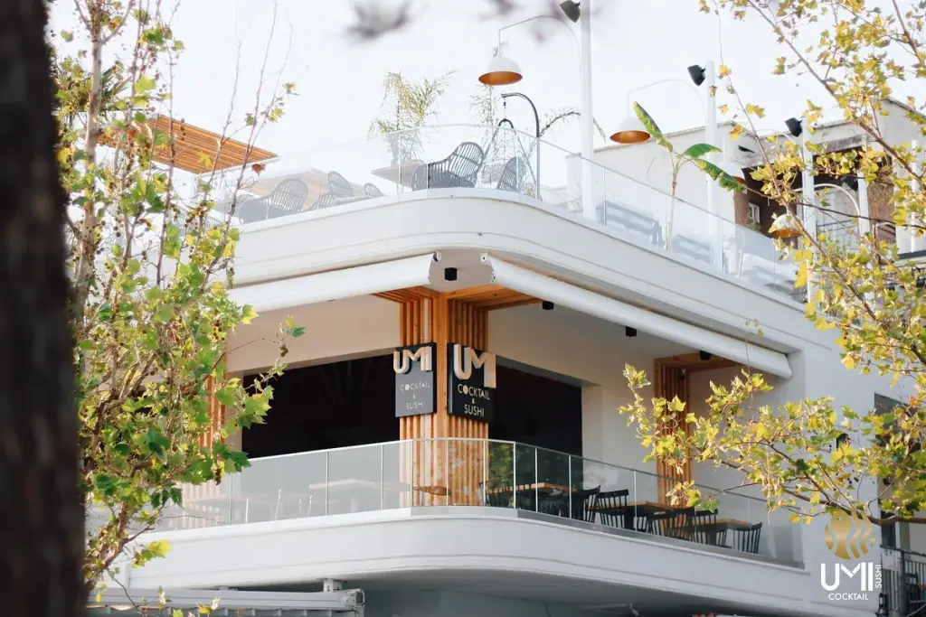 Aerial view of UMI Sushi & Cocktail's rooftop terrace with rows of tables above Himara