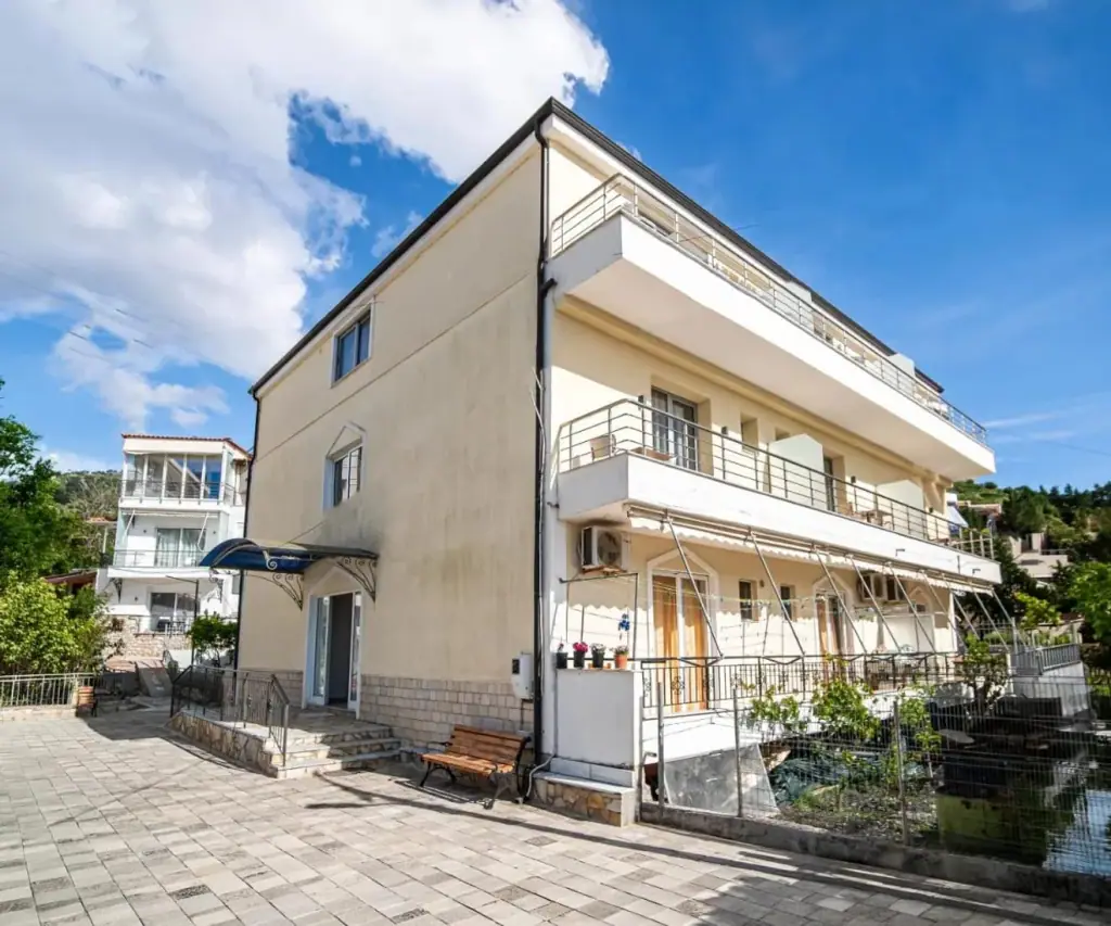 Exterior of Vourtaréa Guesthouse in Potam, Himara, with balconied rooms above a paved forecourt